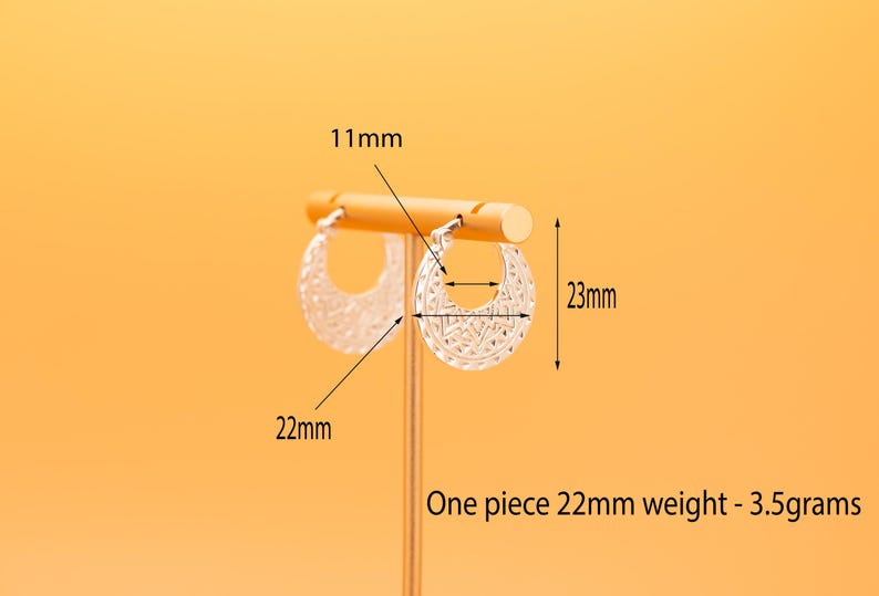 Peut inclure: Une paire de cr&eacute;oles argent&eacute;es avec un motif g&eacute;om&eacute;trique textur&eacute;. Les boucles d'oreilles mesurent 23 mm de hauteur et 22 mm de largeur, avec un diam&egrave;tre int&eacute;rieur de 11 mm. Chaque boucle p&egrave;se 3,5 grammes, comme indiqu&eacute; sur l'image.