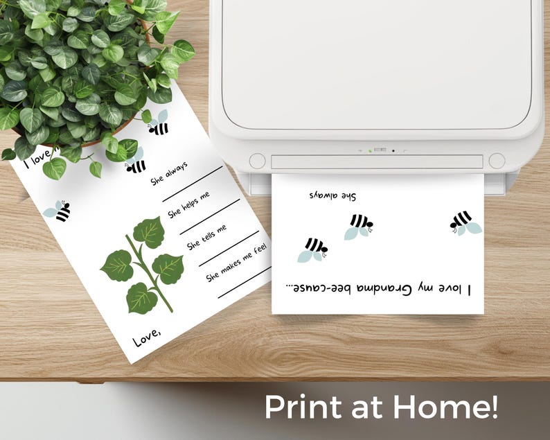 May include: Two white sheets of paper with bee graphics and text are on a wooden surface. One sheet has fill-in-the-blank lines and a leafy vine illustration. The other sheet is printing from a white printer. The text "Print at Home!" is at the bottom.