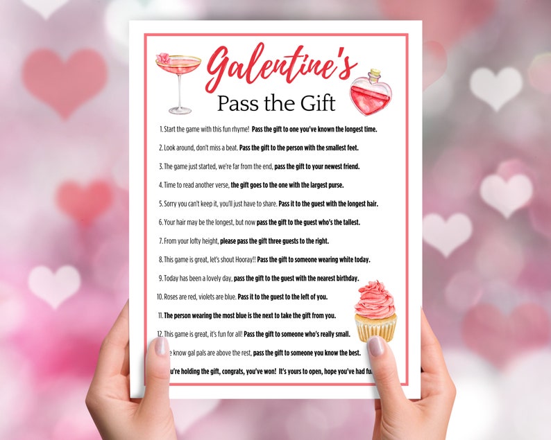 Puede incluir: Una tarjeta de juego imprimible rosa y blanca con el texto "Galentine's Pass the Gift" e instrucciones para un juego de intercambio de regalos. La tarjeta presenta una copa de c&oacute;ctel rosa, una botella de poci&oacute;n roja y una magdalena rosa.
