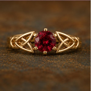 Può includere: Un anello in oro con una pietra preziosa rotonda e sfaccettata di colore rosso intenso al centro. La fascia presenta intricati motivi metallici traforati e simmetrici su entrambi i lati della pietra, creando un design dettagliato e continuo.