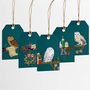 May include: Four teal blue gift tags with twine string, each featuring a different illustration of an owl, a stack of books, a wreath, and a potion bottle. The tags have the text "Christmas Gift" and "A new book" on them.