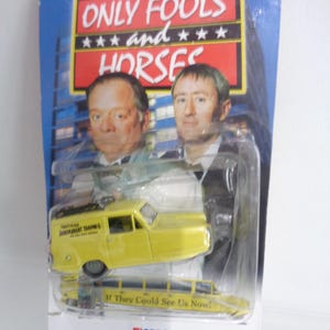 May include: A yellow three-wheeled van toy in original blister packaging featuring the Only Fools and Horses logo and imagery of two men. The van has Trotters Independent Trading printed on the side and If They Could See Us Now! on the base.