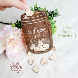 May include: A wooden mason jar-shaped box with the words "I love you because" and several heart-shaped wooden tags. The jar is brown with a clear front, and the tags have phrases like "You are funny" and "Caring". The words "SVG Digital Download" are also visible.