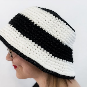 May include: A black and white striped crocheted bucket hat. The hat is made with a thick yarn and has a wide brim.