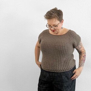 May include: A brown crocheted top with a scoop neck and short sleeves. The top is loose fitting and has a textured stitch pattern.