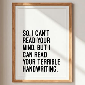 Könnte beinhalten: Ein gerahmter Druck mit dem Text "SO. I CAN'T READ YOUR MIND, BUT I CAN READ YOUR TERRIBLE HANDWRITING." Der schwarze Text ist auf weißem Hintergrund zentriert und in einem hellbraunen Holzrahmen eingefasst. Der Druck hängt an einer weißen Wand.