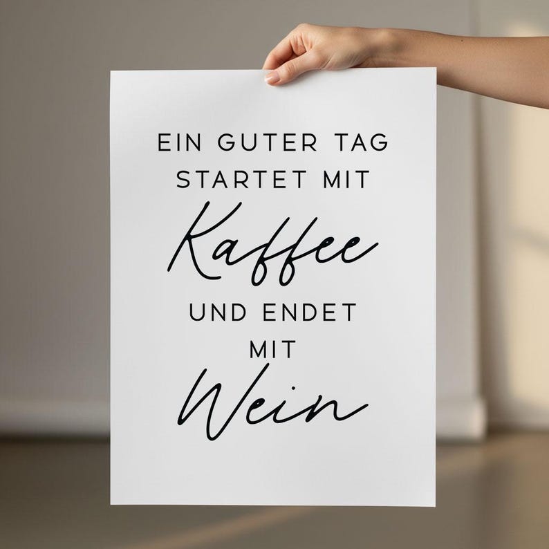 May include: A white poster with black text. The text reads, "EIN GUTER TAG STARTET MIT Kaffee UND ENDET MIT Wein." The poster is held by a hand.