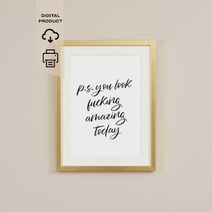 May include: A framed print with the text "p.s. you look fucking amazing today" in black script. The frame is gold, and the print is a digital product. The background is a neutral beige color.