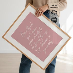 May include: A framed print with a pink background and white script that reads "Beautiful girl, you were made to do hard things. So, believe in yourself." The frame is light brown.