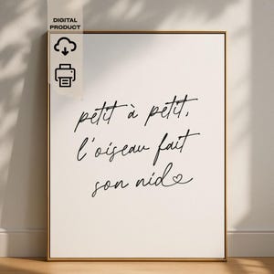 May include: A framed art print with the French phrase "petit à petit, l'oiseau fait son nid" in elegant black script on a cream background. The print is in a gold frame and includes digital product icons.