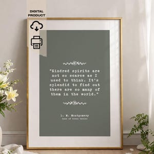 Może przedstawiać: Oprawiony wydruk ze złotą ramą. Wydruk zawiera cytat L.M. Montgomery z Ani z Zielonego Wzgórza na stonowanym zielonym tle. Tekst brzmi: „Pokrewne dusze nie są tak rzadkie, jak myślałem”.