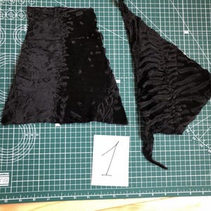 May include: Two pieces of black fabric on a green cutting mat. The fabric has a textured, fuzzy surface. The fabric is labelled with the number "1".