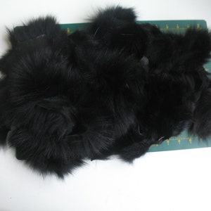 May include: A pile of black fur pieces, possibly pelts or remnants, on a green cutting mat. The fur looks dense and soft, with a deep black colour. The image is taken from a top-down perspective.