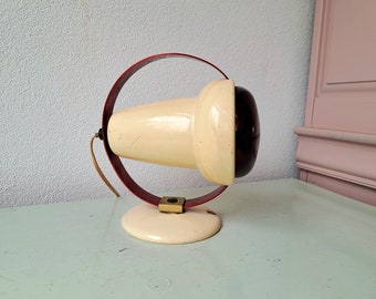 May include: A vintage red and white lamp with a round base and a cone-shaped shade. The shade has a dark red glass insert.