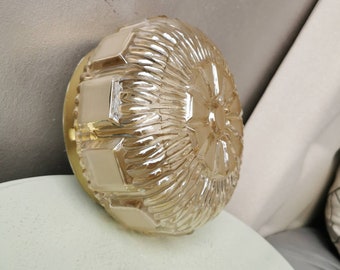 May include: A round, frosted glass ceiling light fixture with a gold metal trim. The glass has a textured, geometric pattern.