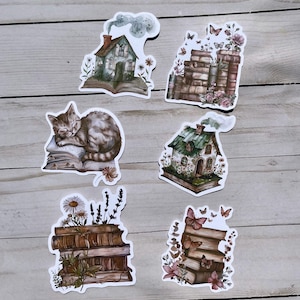 May include: A collection of whimsical stickers featuring a cozy theme. Designs include a sleeping cat on a book, stacks of books with flowers and butterflies, and charming houses with open books. The stickers have a watercolor style with soft colors.