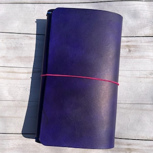 May include: A white ceramic mug with a black handle and the text "But First, Coffee" in a bold, black font. The mug is sitting on a wooden surface. The mug is approximately 4 inches tall.