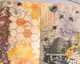 May include: An open journal with a yellow and orange honeycomb pattern on the left page and a black and white illustration of a beehive with bees on the right page. The pages are decorated with flowers and bees.