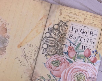 Może przedstawiać: Otwarty, vintage'owy dziennik z dekoracyjnym wzorem kwiatowym. Dziennik ma brązową okładkę o postarzanym wyglądzie i prezentuje wzór kwiatowy z różowymi różami, zielonymi liśćmi i niebieskimi jagodami. Dziennik ma również dekoracyjny, czarno-biały wzór mandali na lewej stronie. Prawa strona zawiera tabelę z literami alfabetu.