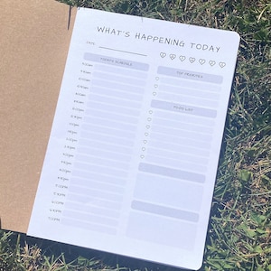 Puede incluir: Un planificador blanco con el texto "What's Happening Today" en la parte superior. El planificador tiene secciones para "Today's Schedule", "Top Priorities" y "To-Do List".