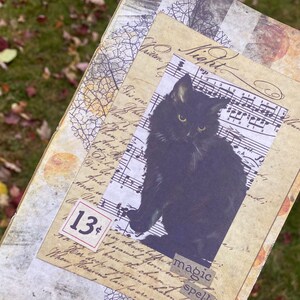 May include: A black cat with green eyes sits on a sheet of music with the word "Night" written in cursive. The music sheet is layered on top of a piece of paper with handwritten text and a price tag that says "13 cents". The image has a vintage aesthetic.