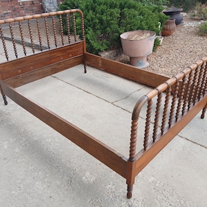 May include: A vintage wooden bed frame with a headboard and footboard featuring turned spindles. The frame is a warm brown color and appears to be made of solid wood. The bed frame is designed for a standard mattress.