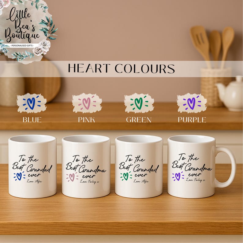 May include: Four white ceramic mugs with the text "To the Best Grandma ever" and a heart graphic in blue, pink, green, and purple. The mugs are on a wooden surface, with the words "HEART COLOURS" above them.