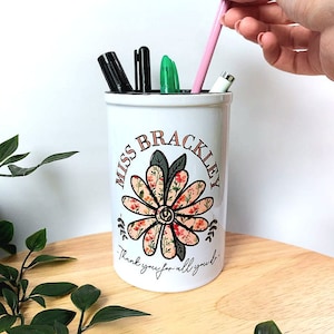 May include: White ceramic pencil holder with a floral design and the text "Miss Brackley Thank you for all you do".