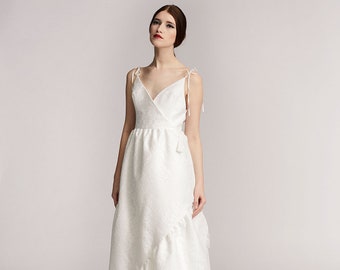 Anna Bridal Wrap Dress- Off white wedding dress in retro floral lace, floor-length, gathered at the waist with a ruffled hem
