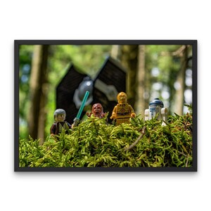 以下が含まれることがあります： 森の背景に、緑の苔の上に立っているスターウォーズのレゴミニフィギュア4体。ミニフィギュアは、ルーク・スカイウォーカー、チューバッカ、C-3PO、R2-D2。背景は、木々と暗い物体のぼやけた画像です。