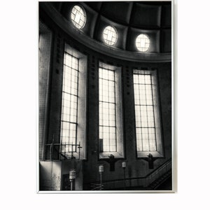 May include: A black and white photograph of a building's interior with a domed ceiling and large windows. The windows are rectangular and have multiple panes. The ceiling has a series of circular windows.
