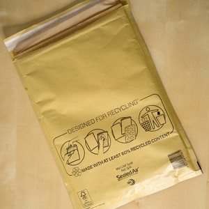 May include: A brown paper mailing envelope with the text "Designed for Recycling" and "Made with at least 60% recycled content". The envelope is labeled "Mail Lite Gold" and "Sealed Air".