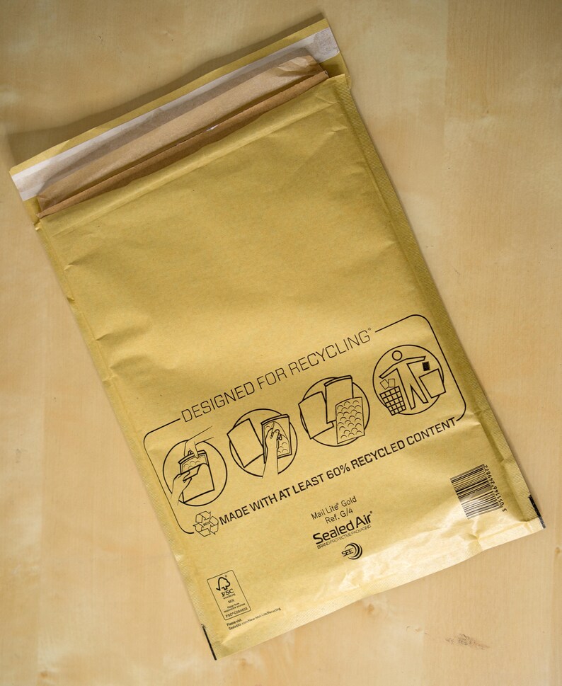 May include: A brown paper mailing envelope with the text "Designed for Recycling" and "Made with at least 60% recycled content". The envelope is labeled "Mail Lite Gold" and "Sealed Air".