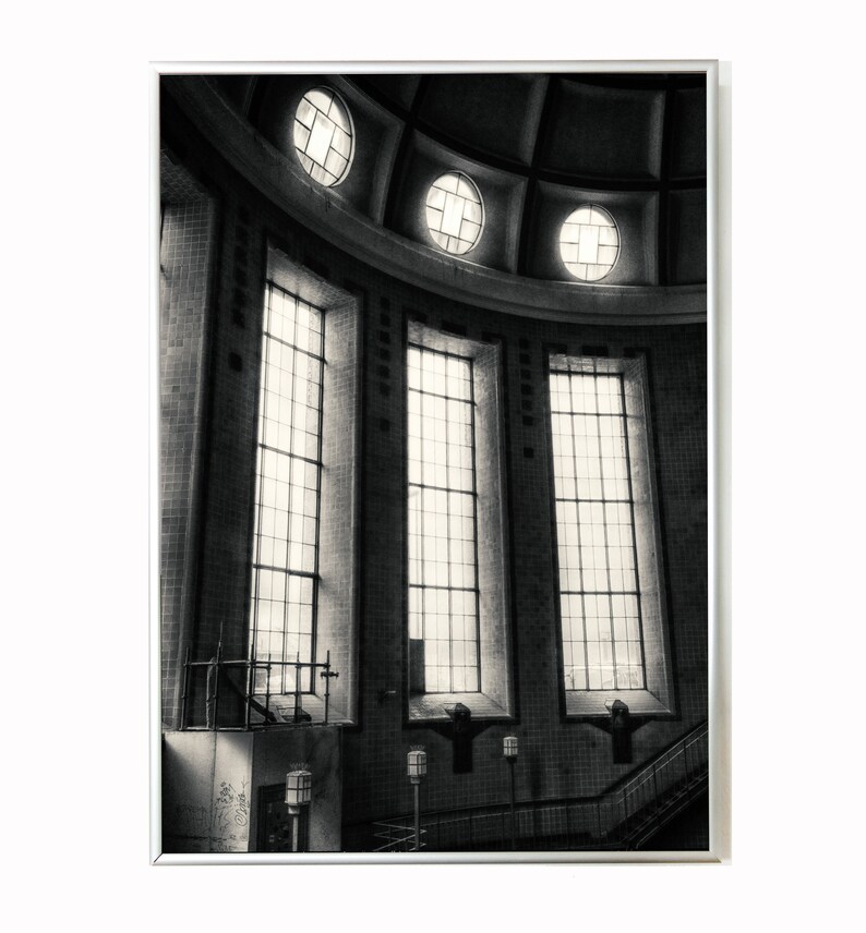 May include: A black and white photograph of a building's interior with a domed ceiling and large windows. The windows are rectangular and have multiple panes. The ceiling has a series of circular windows.
