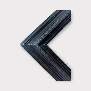 May include: Black picture frame with a decorative, ornate design. The frame is made of wood and has a distressed finish.