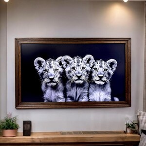May include: A rectangular wall art piece featuring a black and white photograph of three lion cubs side by side against a solid black background, enclosed within a dark brown wooden frame with a textured finish and visible wood grain patterns.