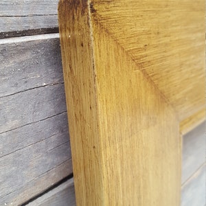 Peut inclure: Gros plan sur le coin d'un cadre photo en bois. Le cadre est de couleur brun clair avec une finition vieillie.