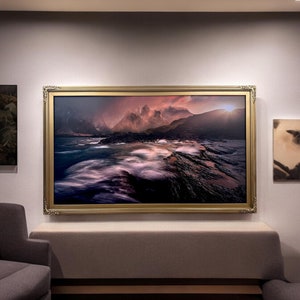 May include: A framed photograph of a dramatic seascape with rocky cliffs and a stormy sky. The image is lit by a warm, golden sunset.