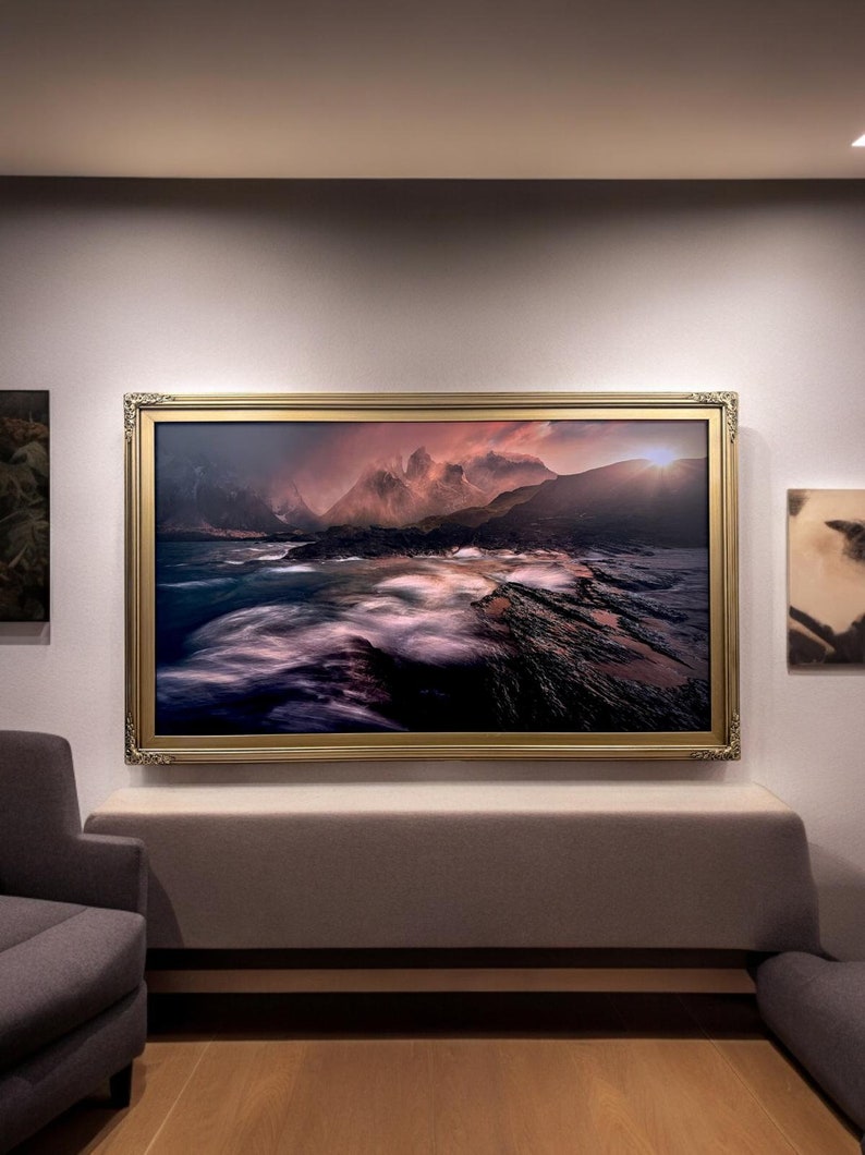 May include: A framed photograph of a dramatic seascape with rocky cliffs and a stormy sky. The image is lit by a warm, golden sunset.