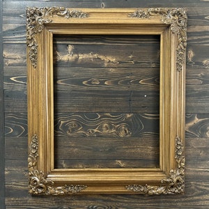 May include: A gold-toned ornate picture frame with a woodgrain background.
