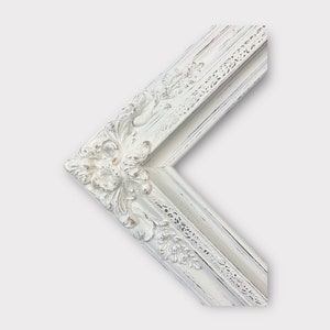 May include: White ornate picture frame with a distressed finish. The frame has a decorative, raised design with floral motifs.