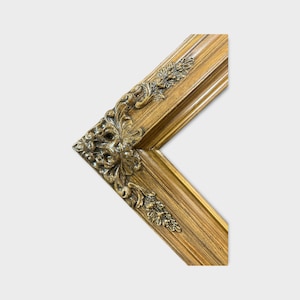 May include: A gold picture frame with ornate detailing around the edges. The frame is made of wood and has a distressed finish.