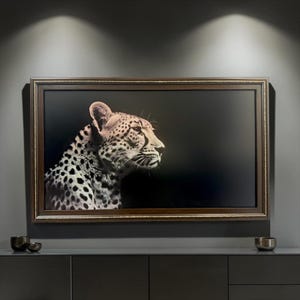 May include: A rectangular wall art piece featuring a high-contrast portrait of a cheetah against a solid black background. The cheetah is shown in profile, facing right, with detailed black spots on its fur. It is encased in a dark brown frame.