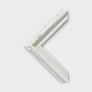 May include: White ornate picture frame with a decorative floral design. The frame is made of wood and has a smooth finish.