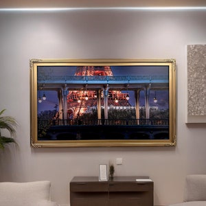 May include: A framed photograph of the Eiffel Tower at night, with the lights of the city in the background. The photo is in a gold frame and is hanging on a wall.
