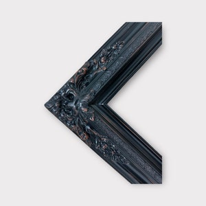May include: Black ornate picture frame with a detailed, carved design. The frame is made of wood and has a dark finish.