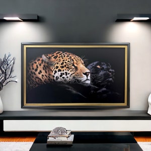 May include: A rectangular wall art piece featuring a detailed portrait of a spotted leopard and a black panther side by side against a dark background. The artwork is enclosed in a thick black frame with a thin gold inner border, mounted on a wall.