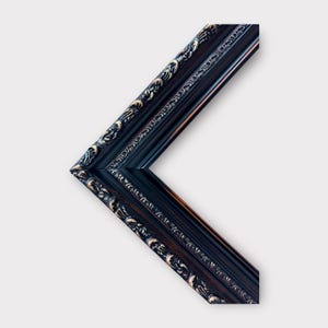 May include: A black picture frame with ornate gold detailing. The frame has a beveled edge and a classic design.