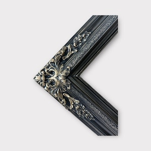 May include: A black picture frame with ornate gold detailing. The frame has a beveled edge and a decorative design.