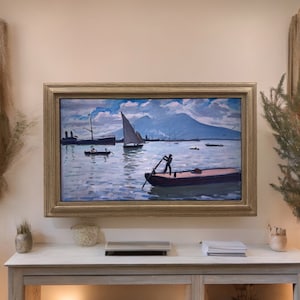 May include: A rectangular landscape painting in a gold frame depicting a harbor scene with several small boats on blue water. A person stands in a foreground boat using an oar, while a large mountain rises in the background under a cloudy sky.